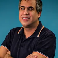 Marlon Brandão de Sousa, arms folded and smiling broadly, against a plain blue studio background.
